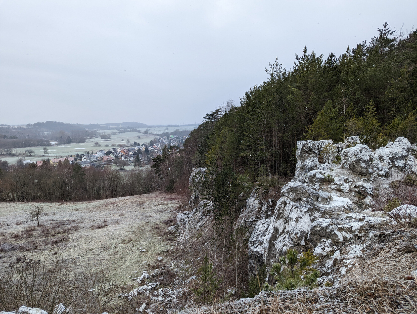 Weißer Gipsfelsen mit Ausblick auf Wald und eine Ortschaft