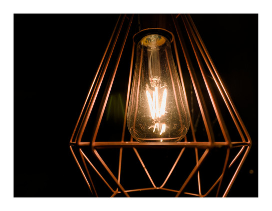 Eine Retro-LED-Leuchtmittel in einer minimalistischen Lampe vor einem dunklen Hintergrund.
