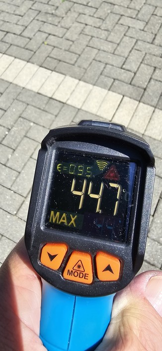 Temperaturmessung mit Digitalgerät von Pflastersteinen in der Sonne. Digitalanzeige 44,7° C