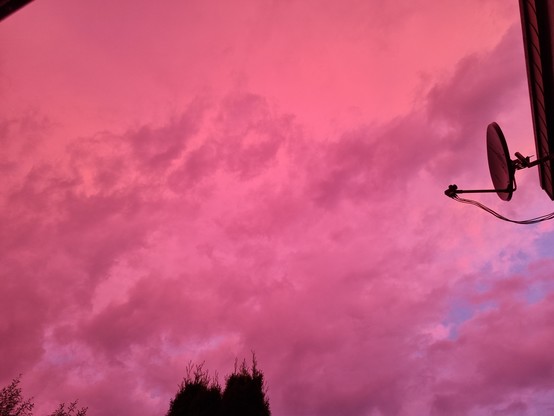 Ein grell rosa-lila gefärbter Abendhimmel.  Der Bildausschnitt ist in etwa der gleiche wie im Bild davor.