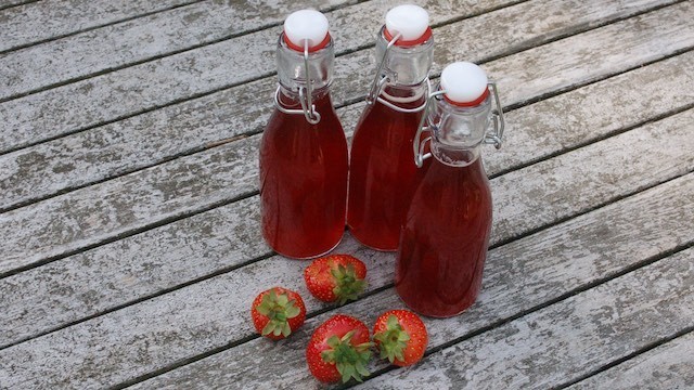 Erdbeersirup mit Minze und Limettensaft in Bügelflaschen mit ein paar Erdbeeren