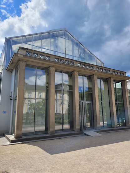 Eingang zum Gewächshaus des Botanischen Garten in Poppelsdorf. Steinsäulen tragen einen kleinen Balkon als Verkleidung des Glasgewächshauses.