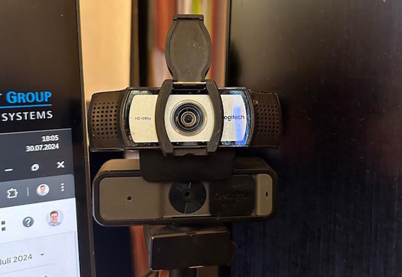 Zwei Webcams auf einem Ständer übereinander, zwischen zwei Monitoren stehend