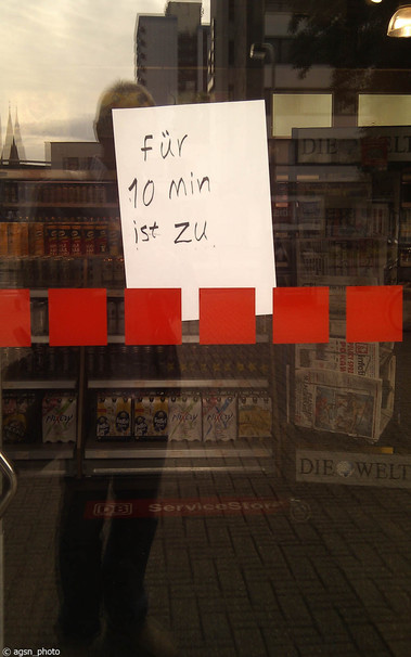 An der geschlossenen Glastür eines kleinen Ladens klebt ein handgeschriebener Zettel mit der Aufschrift 